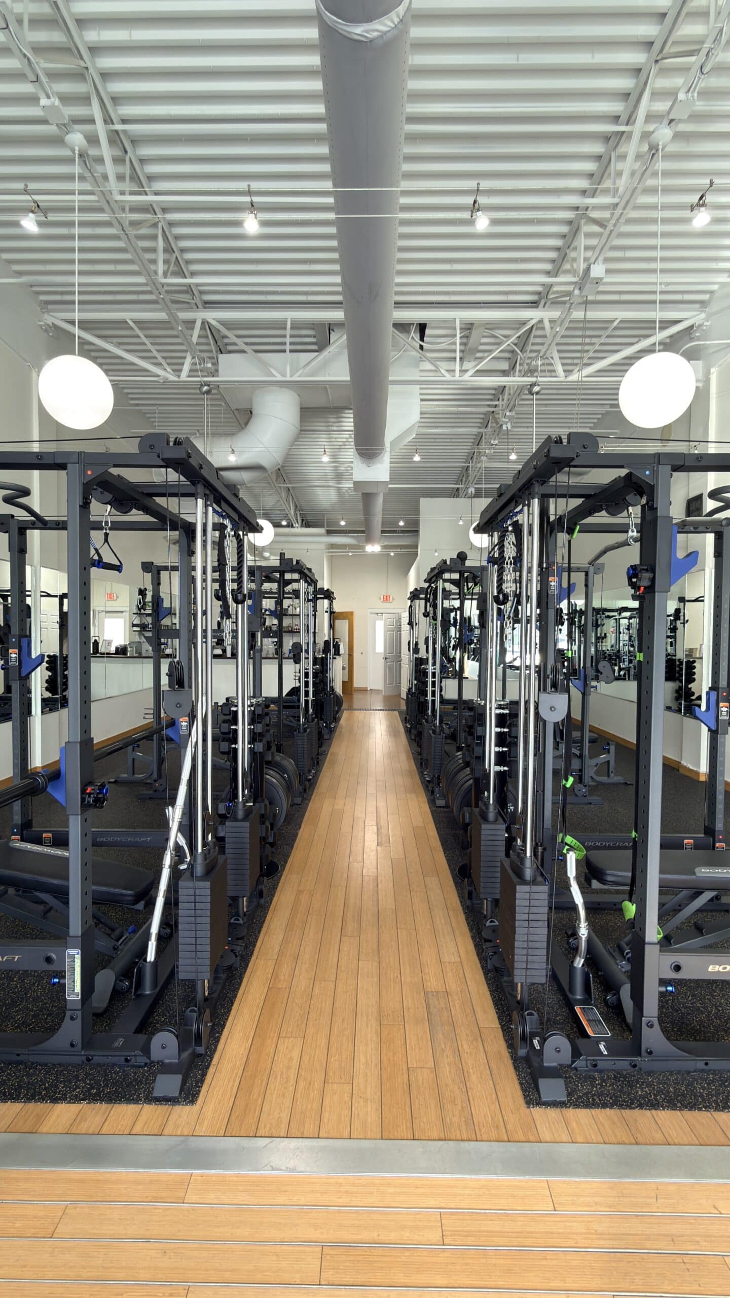 Rows of BodyCraft cable machines line a bright, wood-floor personal training studio in Asheville NC.