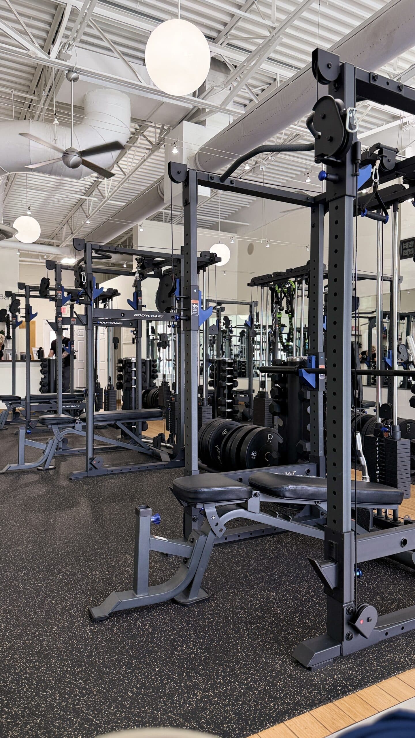 BodyCraft power racks with cable attachments and adjustable benches in a bright Asheville personal training studio.