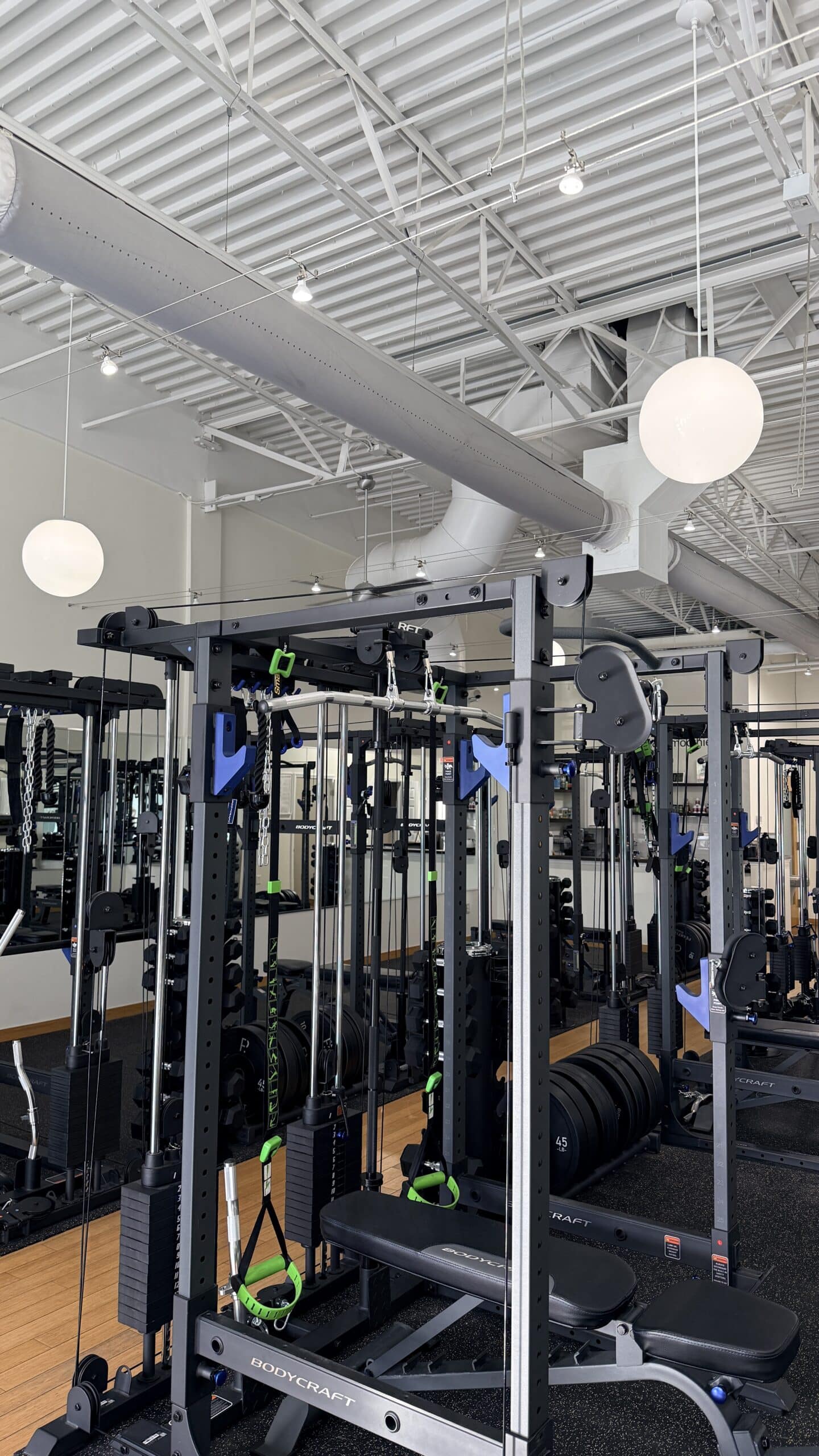 BodyCraft functional trainer cable machine with green resistance bands and weight plates in modern Asheville personal training studio.