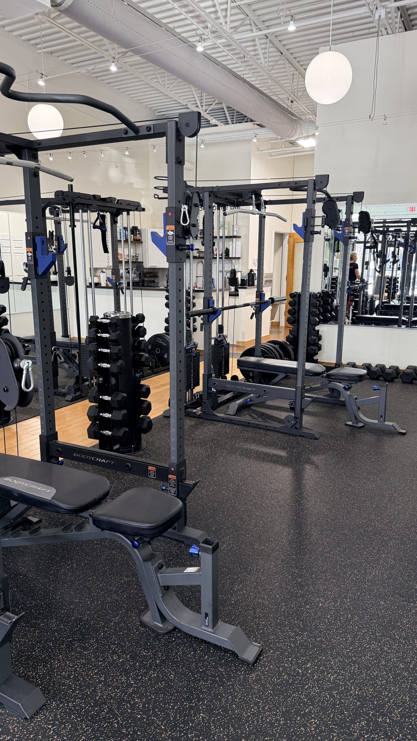 BodyCraft power racks with cable systems, dumbbells, and adjustable benches in a modern Asheville personal training studio.